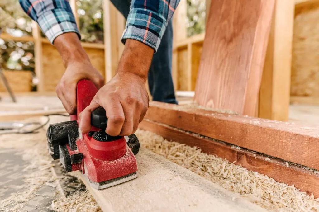 construction worker sanding wood for deck remodel