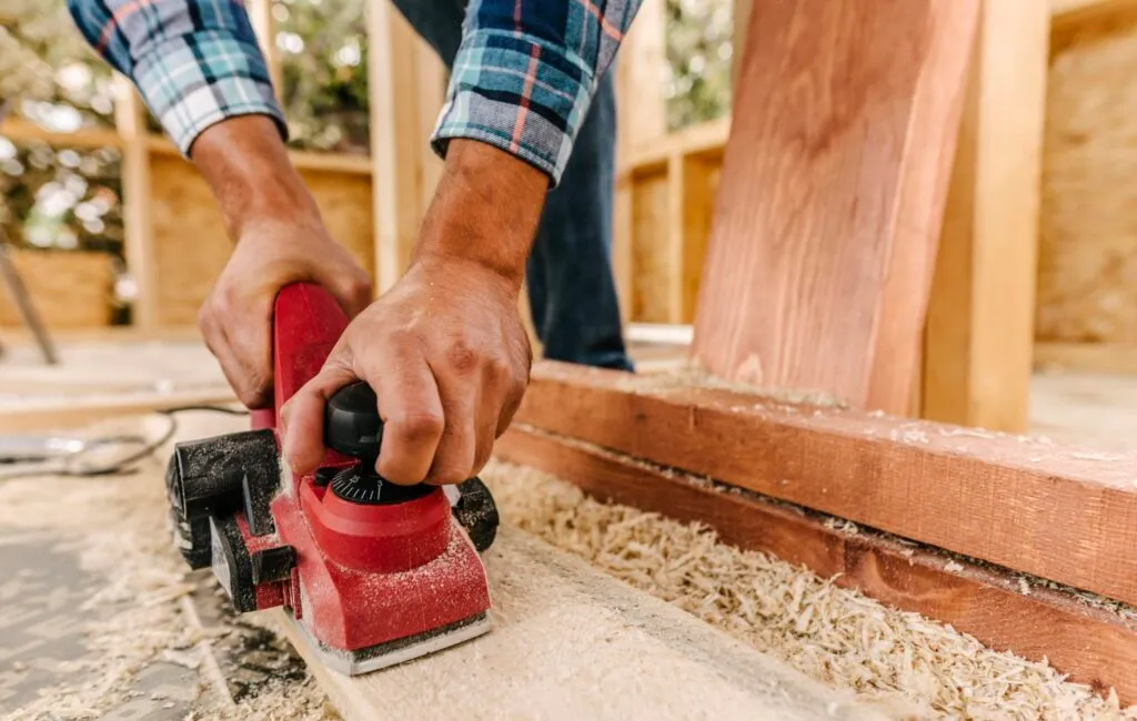 construction worker sanding wood for deck remodel
