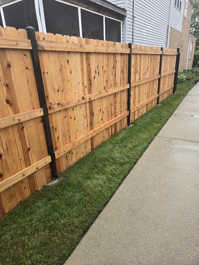 New cedar privacy fence on black steel posts after power washing, before sealing, in Chicago