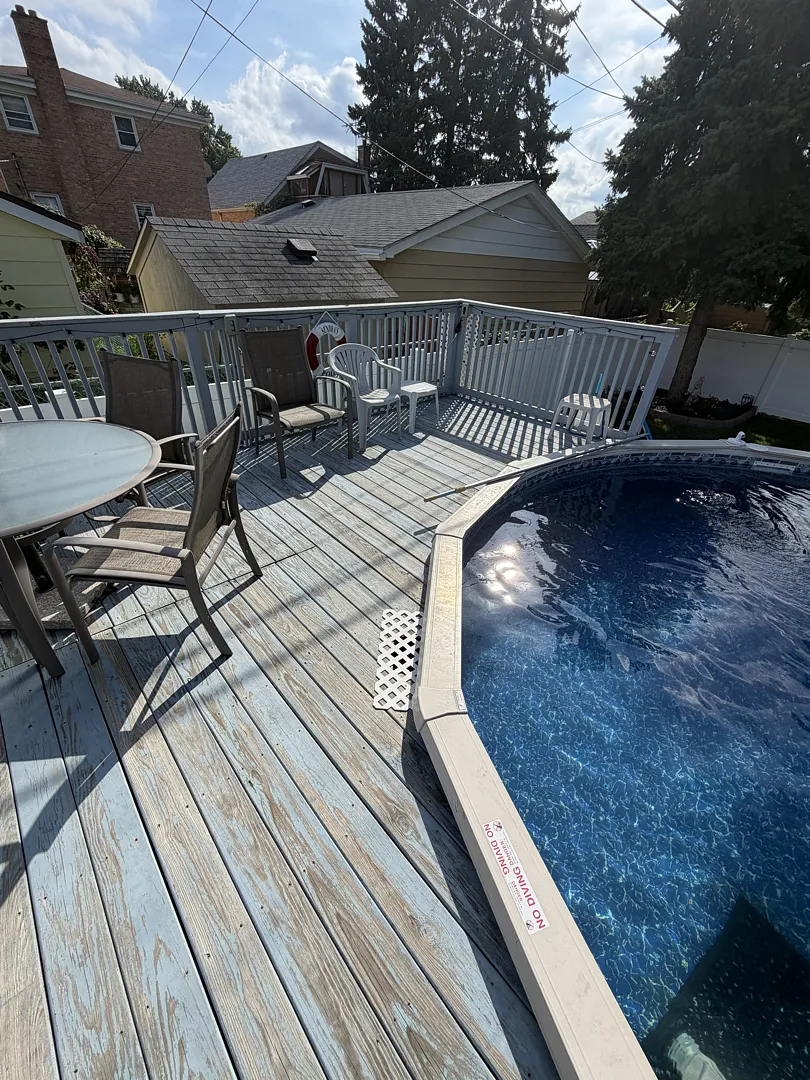 Weathered gray wood pool deck boards running along the edge of an above-ground pool in Chicago