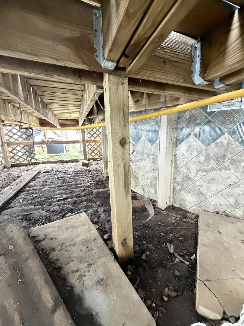 4x4 wood support post under a pool deck between the pool wall and lattice skirting, with a yellow gas line overhead