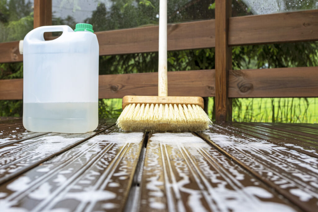 Brush, plastic canister with mortar and soapy water on wooden terrace boards.