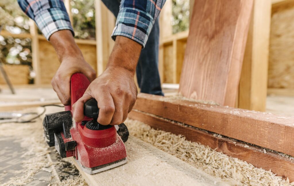 construction worker sanding wood for deck remodel